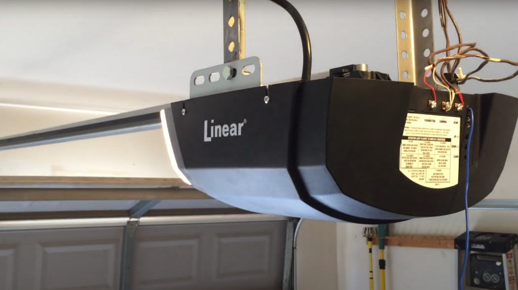 Professional technician installing a high-quality garage door opener in a residential setting, focusing on the installation process with precision tools.