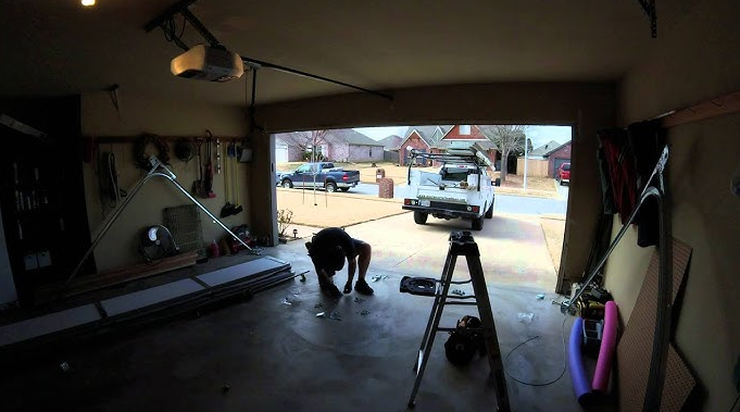 Local garage door repair team in Johnstown, Ohio, working on a residential garage door. The team wears uniforms with the company logo, and a repair van is visible in the background, emphasizing professional mobile service..