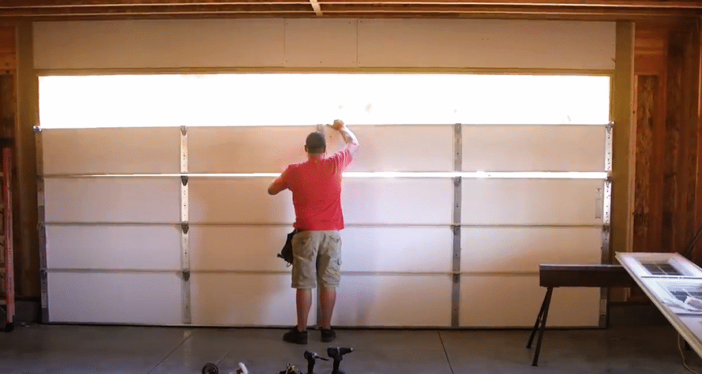 A garage door replacement process showing tools and a newly installed panel.