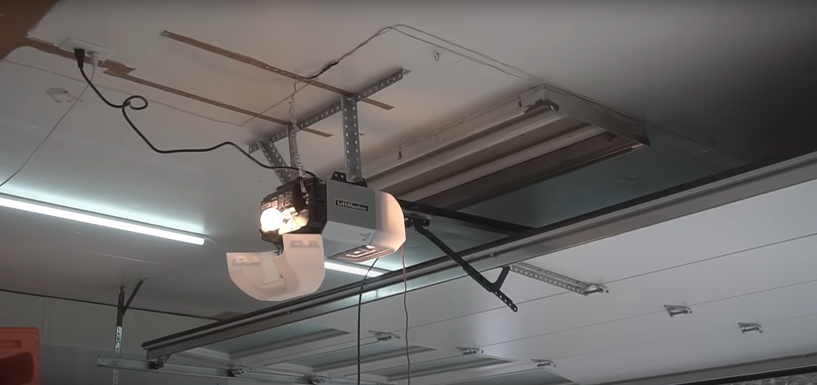 Professional technician installing a high-quality garage door opener in a residential setting, focusing on the installation process with precision tools.